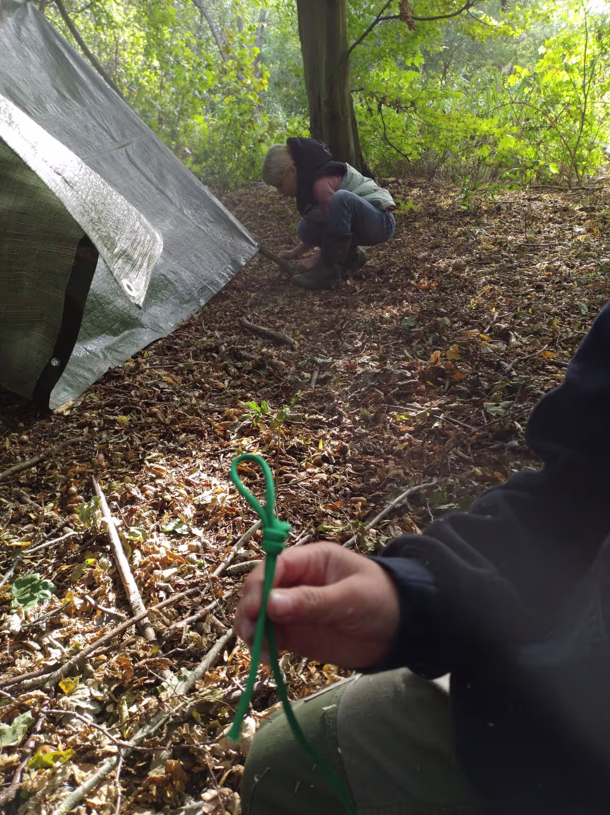 Kinderen bouwen een bivak met eenvoudige materialen tijdens een outdoor workshop in het bos.
