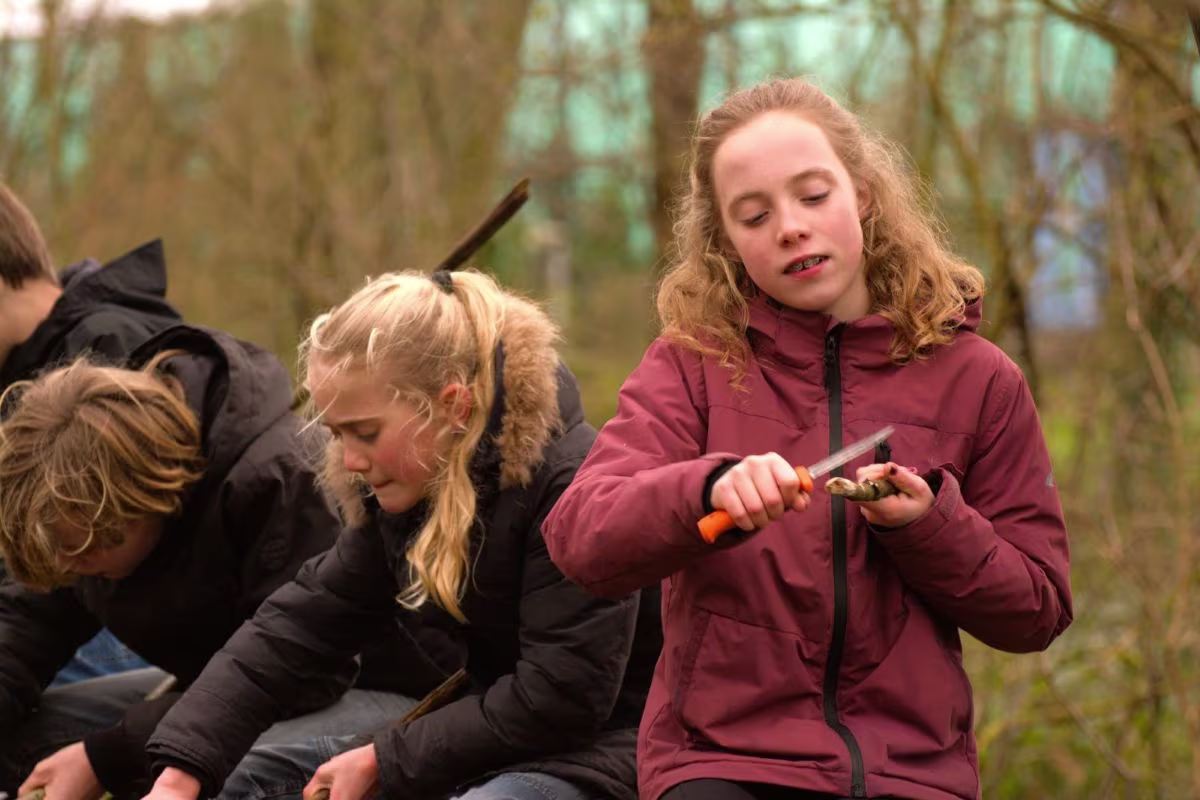 Concentratie tijdens het werken met een mes tijdens de outdoor workshop voor kinderen.