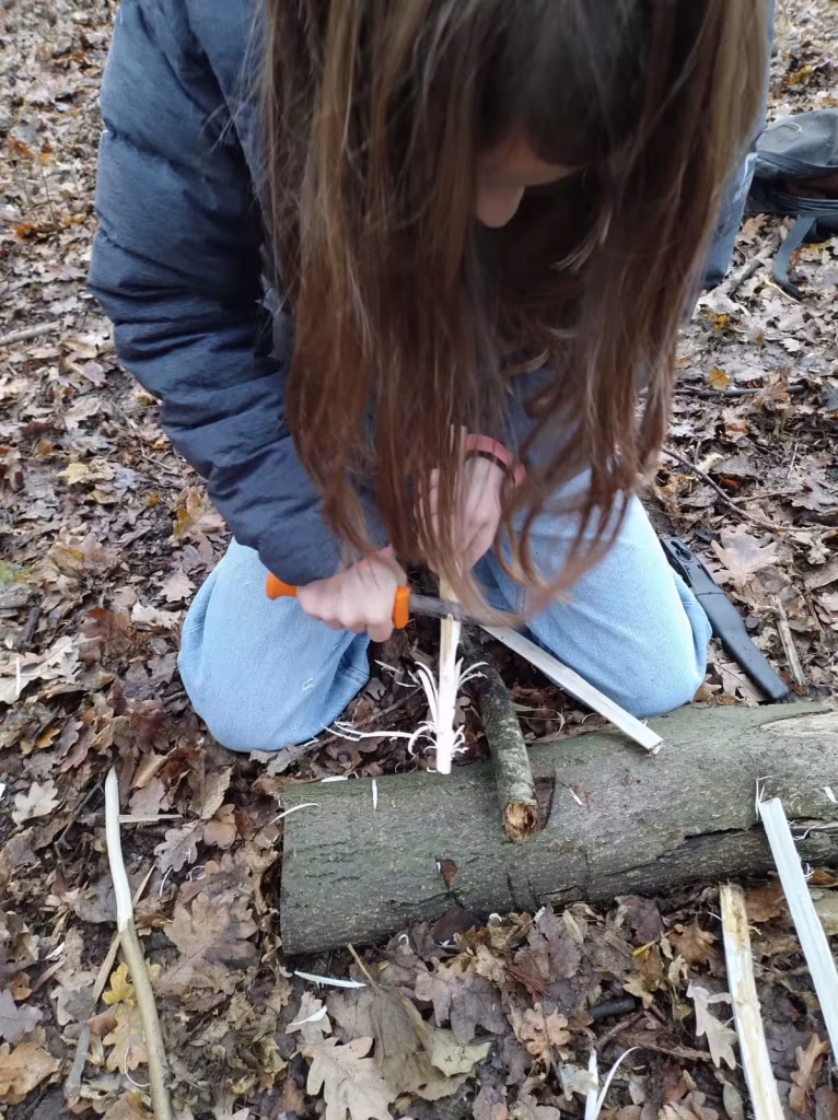 Werken met een mes is een van de outdoor vaardigheden die kinderen leren tijdens een workshop.